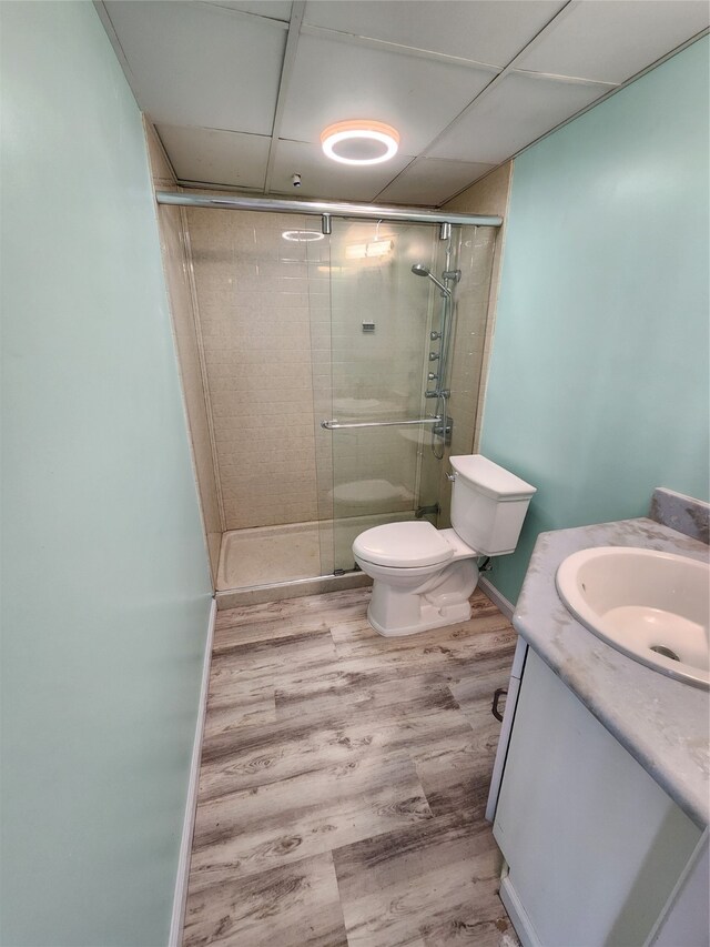 bathroom featuring wood-type flooring, vanity, a shower with shower door, and toilet