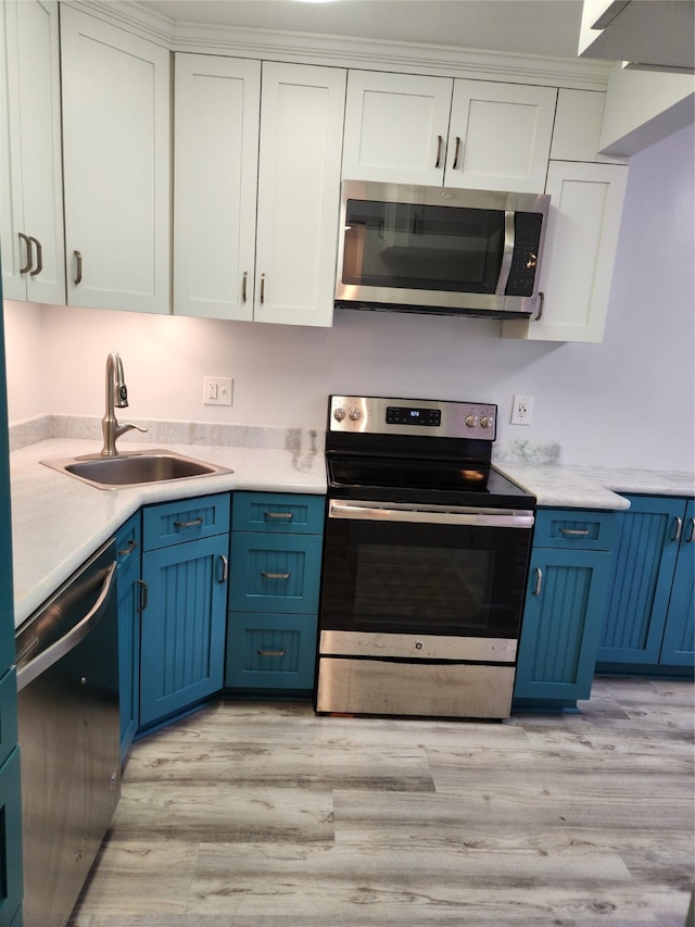 kitchen featuring sink, light hardwood / wood-style flooring, white cabinetry, blue cabinetry, and stainless steel appliances