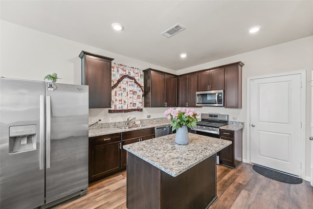 kitchen with wood-type flooring, stainless steel appliances, sink, and a kitchen island