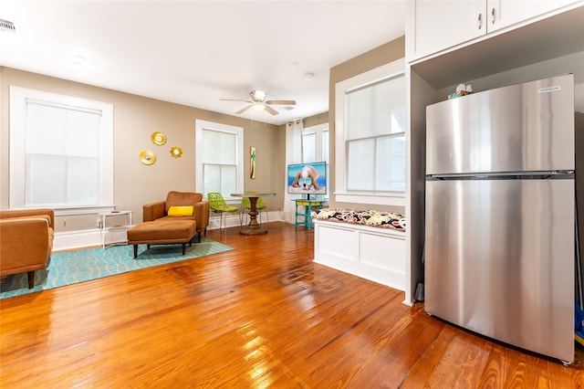 kitchen featuring stainless steel fridge, white cabinetry, ceiling fan, and hardwood / wood-style flooring