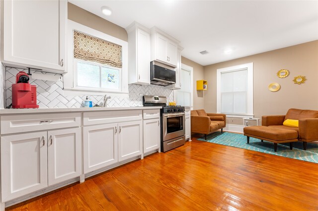 kitchen featuring white cabinetry, light hardwood / wood-style floors, appliances with stainless steel finishes, and tasteful backsplash