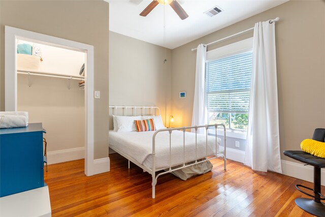 bedroom with ceiling fan, a closet, hardwood / wood-style floors, and a walk in closet