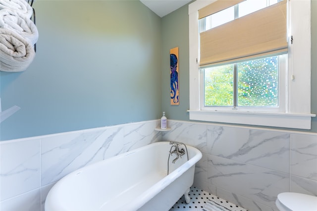 bathroom with tile walls, tile patterned flooring, toilet, and a tub