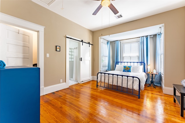 bedroom featuring a barn door, wood-type flooring, and ceiling fan