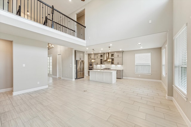 unfurnished living room featuring an inviting chandelier, a towering ceiling, and sink