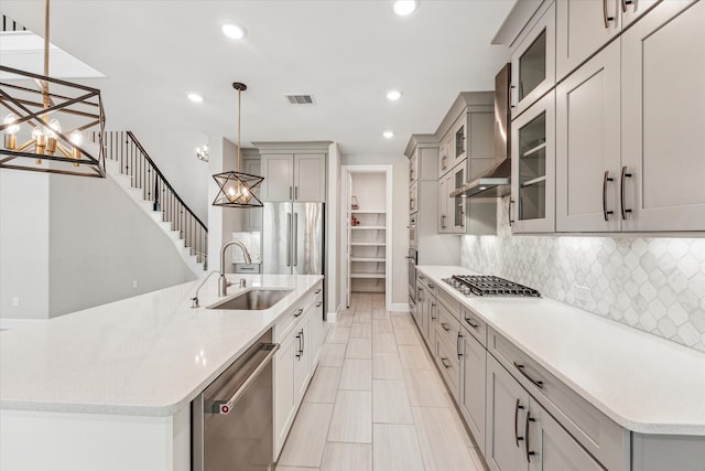 kitchen featuring sink, a notable chandelier, stainless steel appliances, a center island with sink, and decorative light fixtures