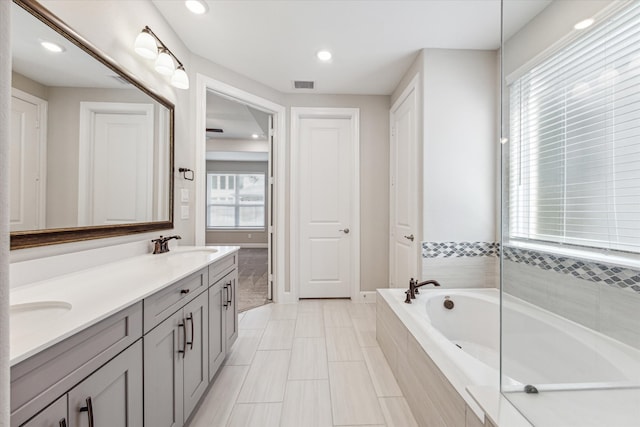 bathroom with vanity and a relaxing tiled tub