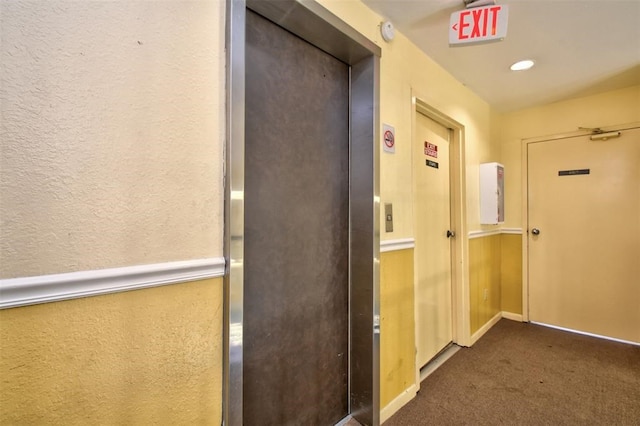 hall featuring dark carpet and elevator