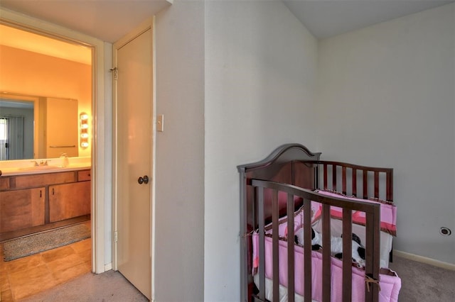 bedroom featuring connected bathroom, light colored carpet, a nursery area, and sink