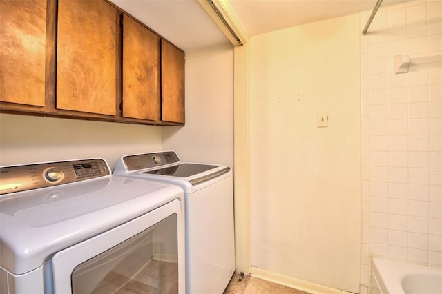 clothes washing area featuring washing machine and clothes dryer and cabinets