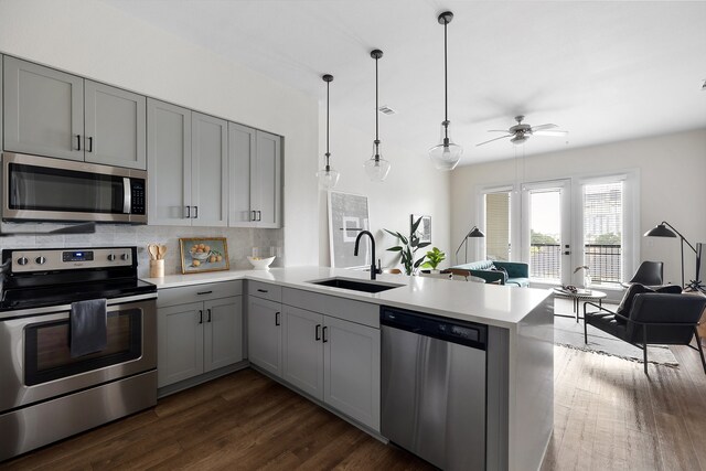 kitchen with kitchen peninsula, appliances with stainless steel finishes, dark wood-type flooring, and sink