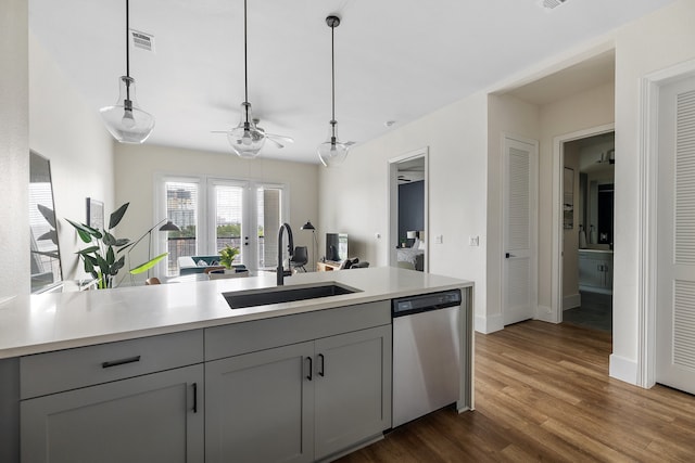 kitchen featuring hanging light fixtures, dark wood-type flooring, gray cabinets, stainless steel dishwasher, and sink