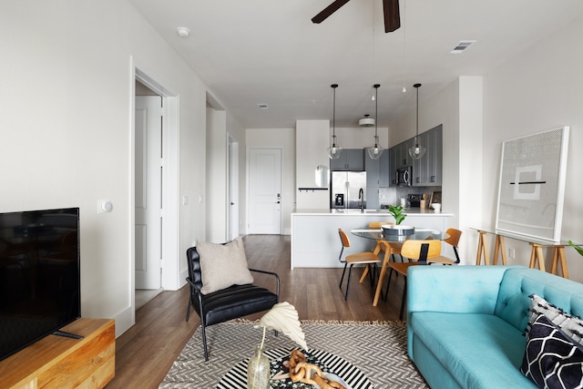 living room featuring sink, dark wood-type flooring, and ceiling fan