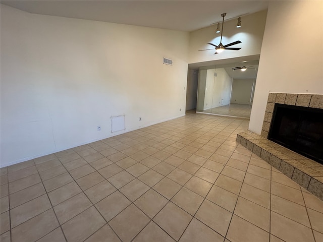 unfurnished living room featuring light tile patterned flooring, ceiling fan, a tiled fireplace, and high vaulted ceiling