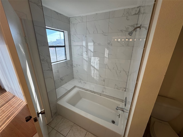 bathroom featuring toilet and tiled shower / bath