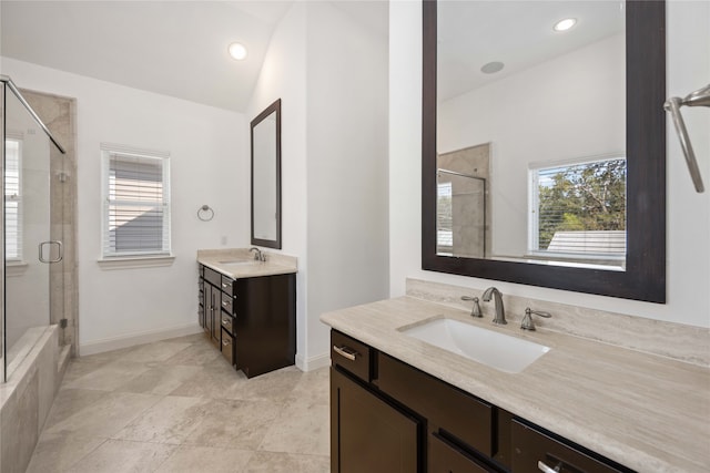 bathroom with vanity, a shower with shower door, and vaulted ceiling