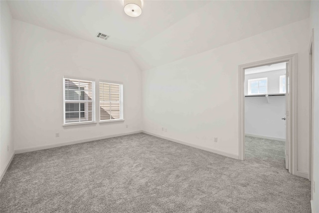 unfurnished room with light carpet, vaulted ceiling, and a healthy amount of sunlight