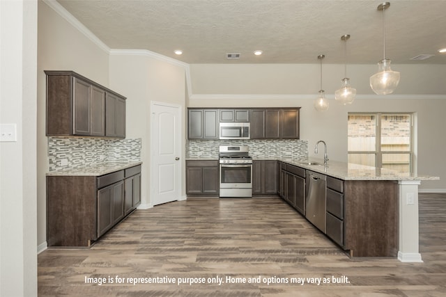 kitchen featuring appliances with stainless steel finishes, kitchen peninsula, light stone counters, and hardwood / wood-style flooring