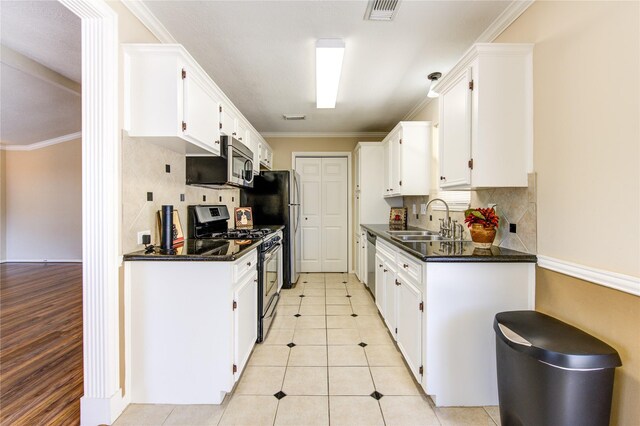 kitchen featuring light tile patterned flooring, appliances with stainless steel finishes, white cabinets, and sink