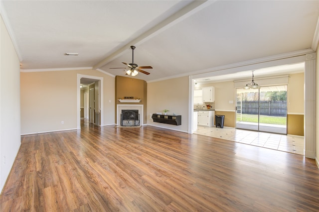 unfurnished living room featuring a fireplace, lofted ceiling with beams, hardwood / wood-style flooring, ornamental molding, and ceiling fan with notable chandelier