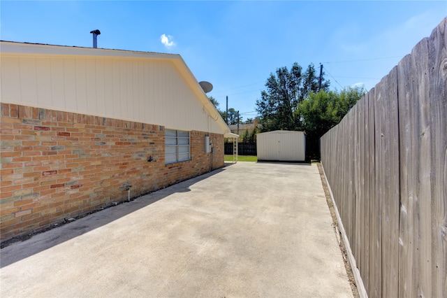 view of side of home featuring a storage unit and a patio