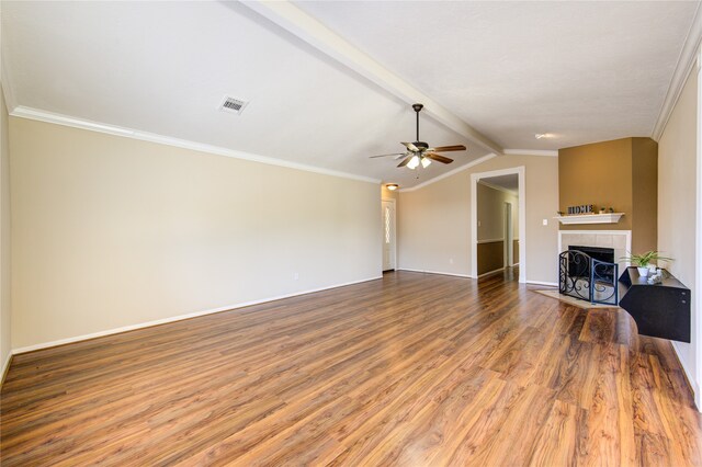 unfurnished living room featuring ceiling fan, a tile fireplace, hardwood / wood-style floors, vaulted ceiling with beams, and crown molding