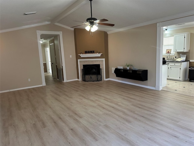 unfurnished living room featuring light hardwood / wood-style floors, a tile fireplace, crown molding, and lofted ceiling with beams