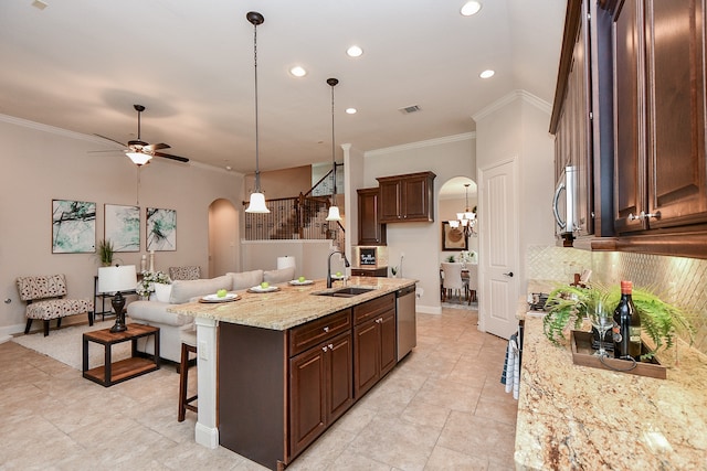 kitchen with pendant lighting, light stone counters, sink, appliances with stainless steel finishes, and ornamental molding