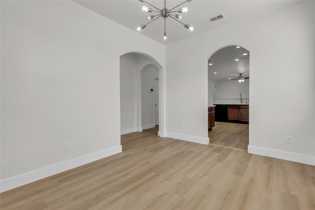 spare room featuring sink, ceiling fan with notable chandelier, and light hardwood / wood-style floors