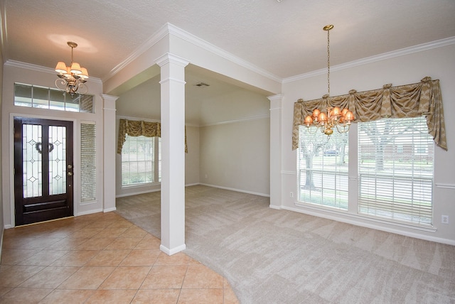 carpeted foyer entrance with a notable chandelier, a textured ceiling, ornamental molding, and ornate columns