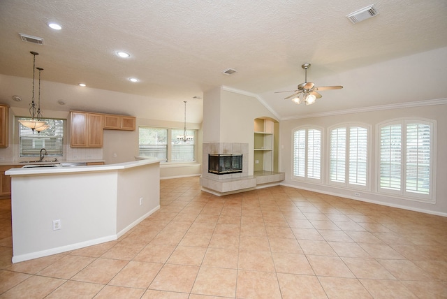 kitchen with vaulted ceiling, ceiling fan, a fireplace, and light tile patterned floors