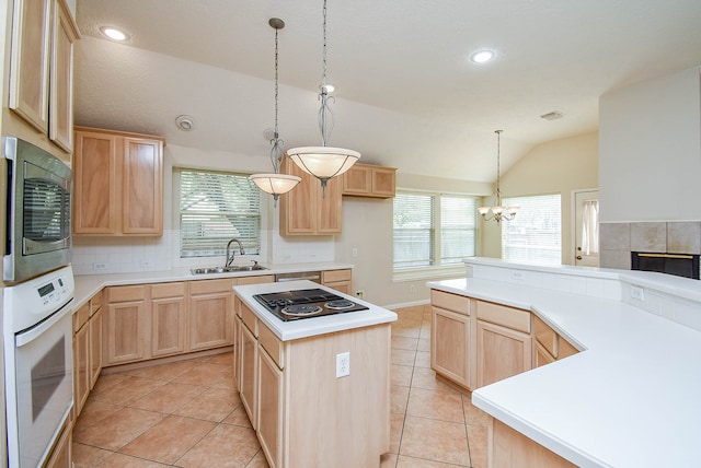 kitchen featuring light brown cabinets, lofted ceiling, sink, appliances with stainless steel finishes, and a center island