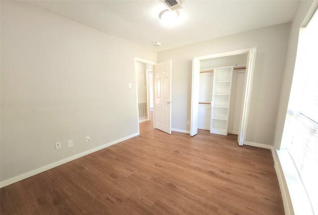 unfurnished bedroom featuring light wood-type flooring, multiple windows, and a closet