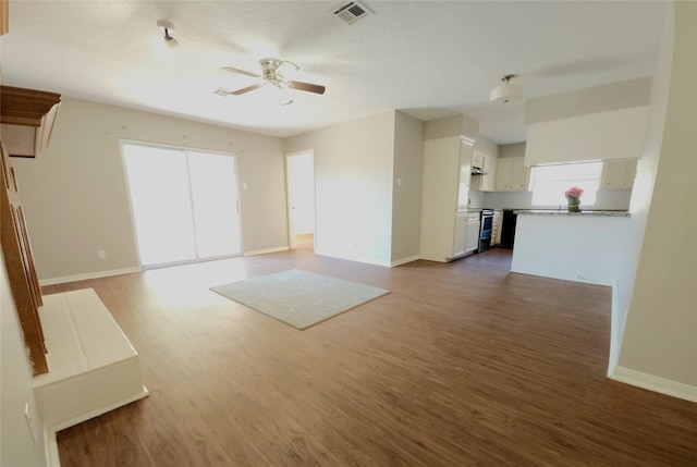 unfurnished living room featuring a textured ceiling, ceiling fan, and dark hardwood / wood-style flooring