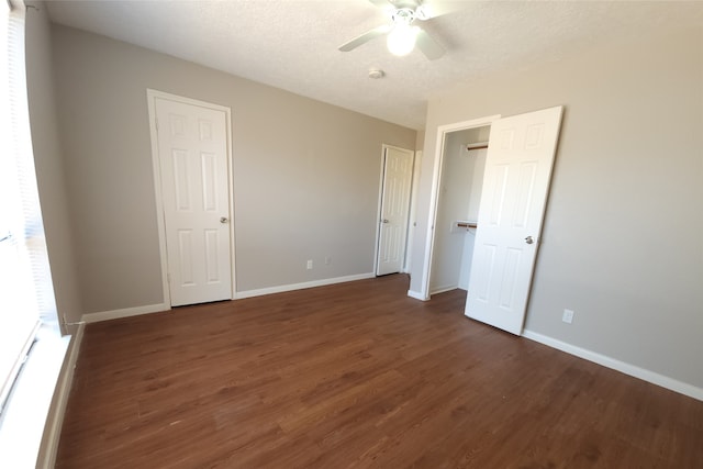 unfurnished bedroom with ceiling fan, a textured ceiling, and dark hardwood / wood-style flooring