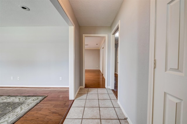 corridor with a textured ceiling and light tile patterned floors