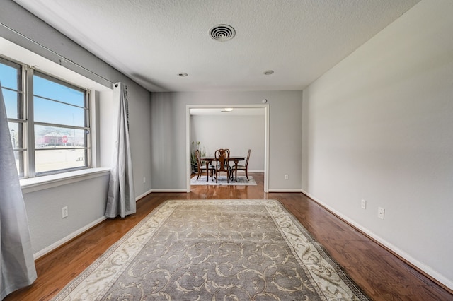 spare room featuring wood-type flooring and a textured ceiling