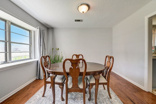 dining area with a textured ceiling and wood-type flooring