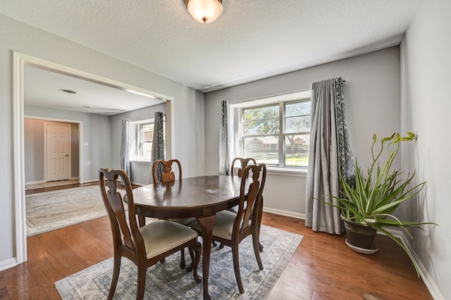 dining space featuring a textured ceiling and hardwood / wood-style floors