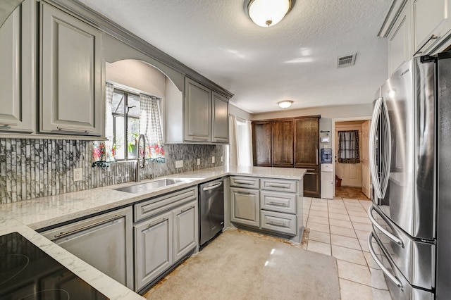 kitchen with appliances with stainless steel finishes, light tile patterned floors, gray cabinetry, and sink