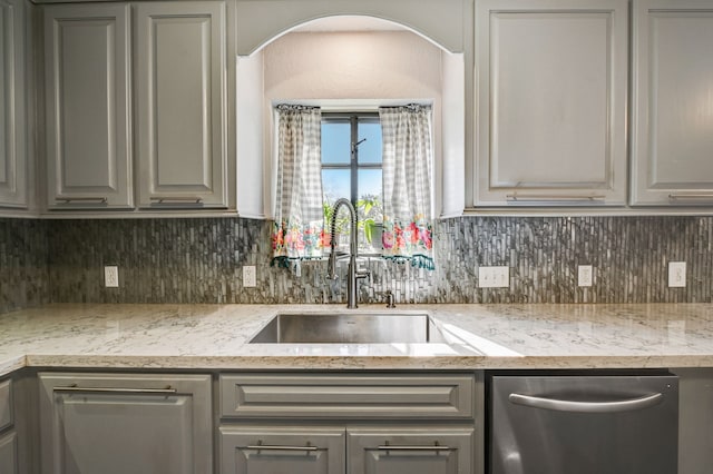 kitchen with sink, gray cabinetry, light stone counters, and backsplash