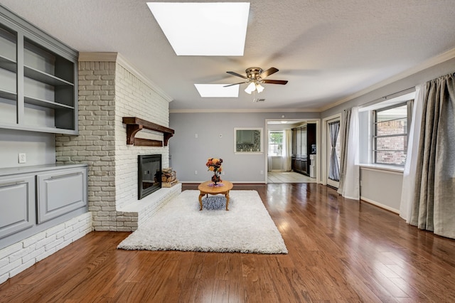 living room featuring ceiling fan, crown molding, a skylight, and a wealth of natural light