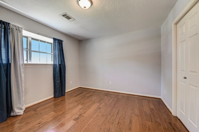 empty room featuring hardwood / wood-style flooring and a textured ceiling