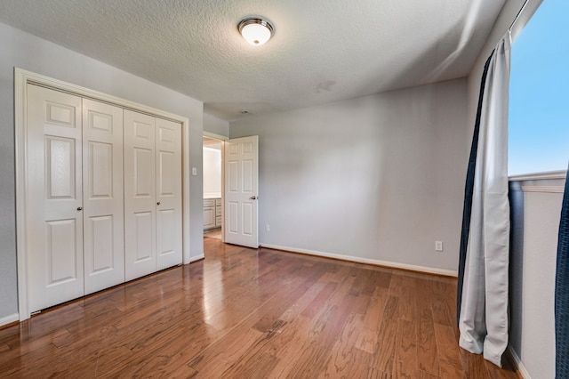 unfurnished bedroom with a textured ceiling, a closet, and hardwood / wood-style floors