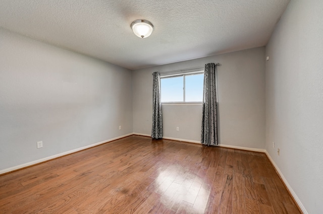 unfurnished room with a textured ceiling and hardwood / wood-style flooring