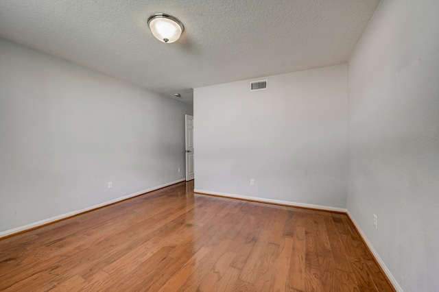 unfurnished room with hardwood / wood-style flooring and a textured ceiling