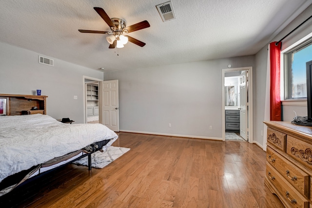 bedroom with ceiling fan, connected bathroom, light hardwood / wood-style floors, and a textured ceiling