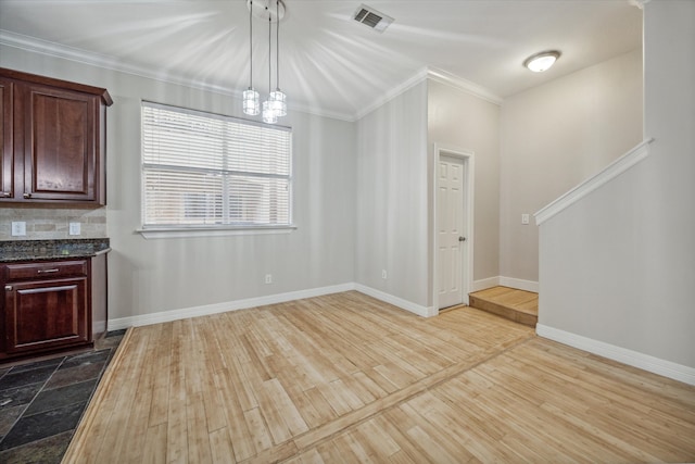 unfurnished dining area with a notable chandelier, light hardwood / wood-style flooring, and ornamental molding