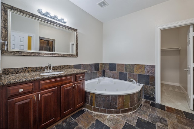 bathroom featuring tiled tub and vanity