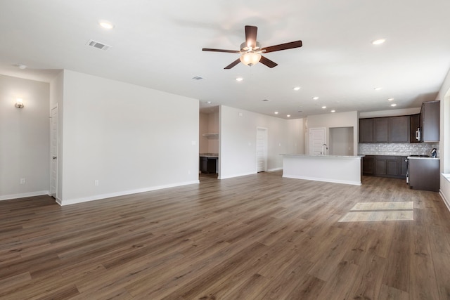 unfurnished living room with dark hardwood / wood-style flooring and ceiling fan